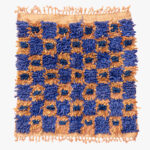 Handgeweven Berber tapijt met koningsblauwe en karamelkleurige patronen, omlijst door natuurlijke zandkleurige franjes.