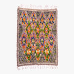 Kleurrijk berber tapijt met handgeweven geometrische patronen in paars, oranje, groen op een grijze achtergrond.