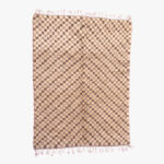 Beige en bruin berber tapijt met visgraatpatroon en roze franjes, handgeweven van natuurlijke wol.