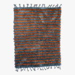Handgeweven berber tapijt met oranje en blauwe strepen en speelse kwastjes, brengt een levendige sfeer in elk interieur.