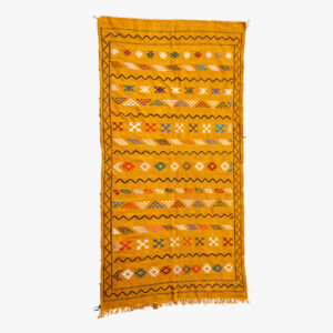 Geel berber tapijt met meerkleurige patronen en traditionele Berber symbolen, afgewerkt met franjes.
