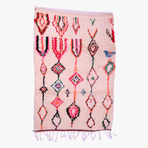 Handgeweven roze berber tapijt met kleurrijke geometrische en tribale patronen, versierd met delicate franjes.