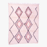 Handgeweven berber tapijt met koraalroze en groene ruitpatronen op een zachte crèmekleurige achtergrond, afgewerkt met franjes.