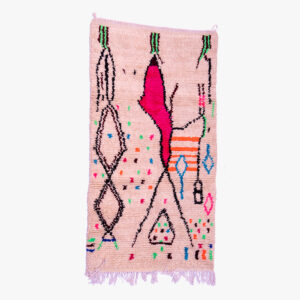 Handgeweven berber tapijt met abstracte patronen in roze, zwart, en kleurrijke accenten, met traditionele franjes aan de randen.