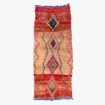 Handgeweven Berber tapijt met kleurrijke geometrische patronen en rijke rode accenten op een beige ondergrond, perfect voor een huiselijke sfeer.