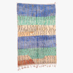 Handgeweven berber tapijt met een veelzijdig patroon in blauw, groen, beige en terracotta, perfect voor een sfeervolle en traditionele huisdecoratie.