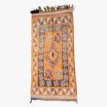 Traditioneel berber tapijt met een diversiteit aan kleuren, waaronder oranje, paars en groen, met kenmerkende geometrische patronen.