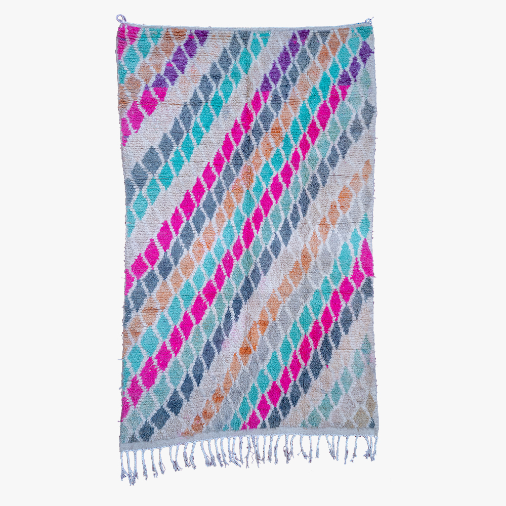 Kleurrijk berber tapijt met zigzagpatroon in tinten paars, blauw, oranje en grijs, afgewerkt met kwastjes.