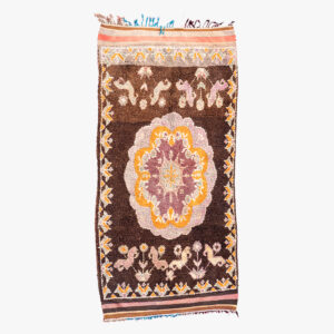 Traditioneel berber tapijt met een centraal medaillon in crème en goud, omgeven door bruine achtergrond en diermotieven.