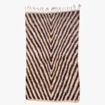 Handgeweven berber tapijt met een opvallend zigzagpatroon in beige en zwart, ideaal voor een hedendaags interieur.
