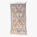 Traditioneel Berber tapijt met een ingewikkeld ontwerp in blauwe, beige en bruine tinten, met fransjes aan de uiteinden, ideaal voor huisdecoratie.