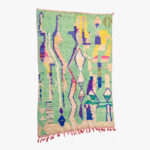 Abstract en kleurrijk Berber tapijt met een dynamisch patroon van geometrische en organische vormen in groen, blauw, geel en roze.