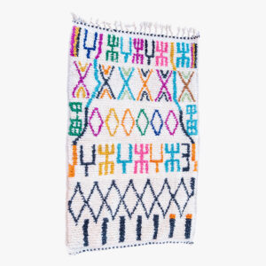 Kleurrijk Berber tapijt met traditionele patronen in blauw, roze, oranje en groen, met handgemaakte fransjes, ideaal voor een speelse ruimte.