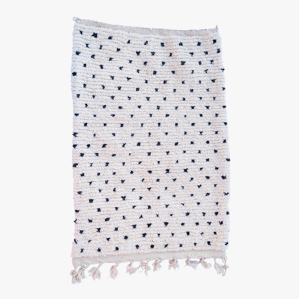 Minimalistisch wit Berber tapijt met discrete marineblauwe stippen en frisse fransjes, een elegante toevoeging aan elk hedendaags interieur.