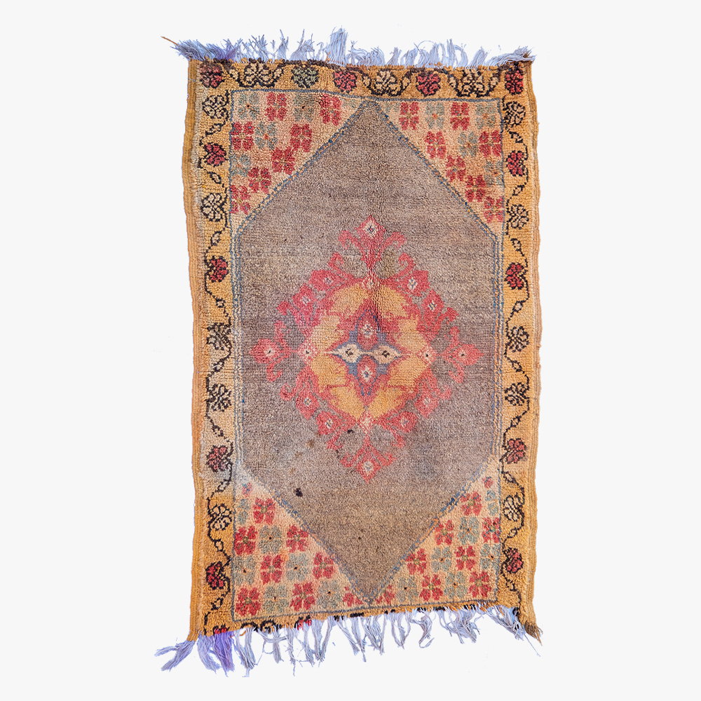 Traditioneel Berber tapijt met centraal diamantmedaillon in rode en oranje tinten, omgeven door een decoratieve aardekleurige rand met bloempatronen.