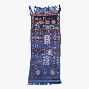 Traditioneel Berber tapijt in diepblauw met een rijk patroon van etnische symbolen en oranje bloemmotieven, met karakteristieke franjes.