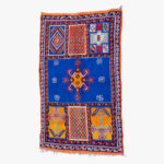 Handgemaakt berber tapijt met traditioneel geometrisch patroon in blauw, oranje en wit.