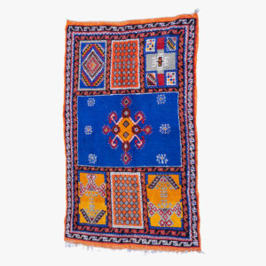 Handgemaakt berber tapijt met traditioneel geometrisch patroon in blauw, oranje en wit.