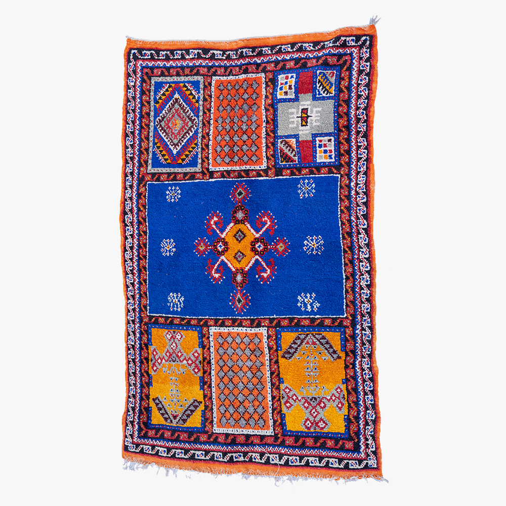 Handgemaakt berber tapijt met traditioneel geometrisch patroon in blauw, oranje en wit.