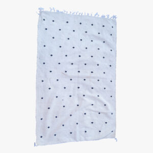 Licht berber tapijt met discrete blauwe stippen en franjes, ideaal voor een elegante en ingetogen huisdecoratie.