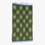 Groen berber tapijt met schaakbordpatroon en witte geometrische symbolen, omzoomd met lichtblauwe franjes.