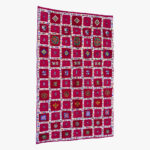 Berber tapijt met een rijk patroon van kleurrijke vierkanten en traditionele motieven op een dieprode achtergrond.